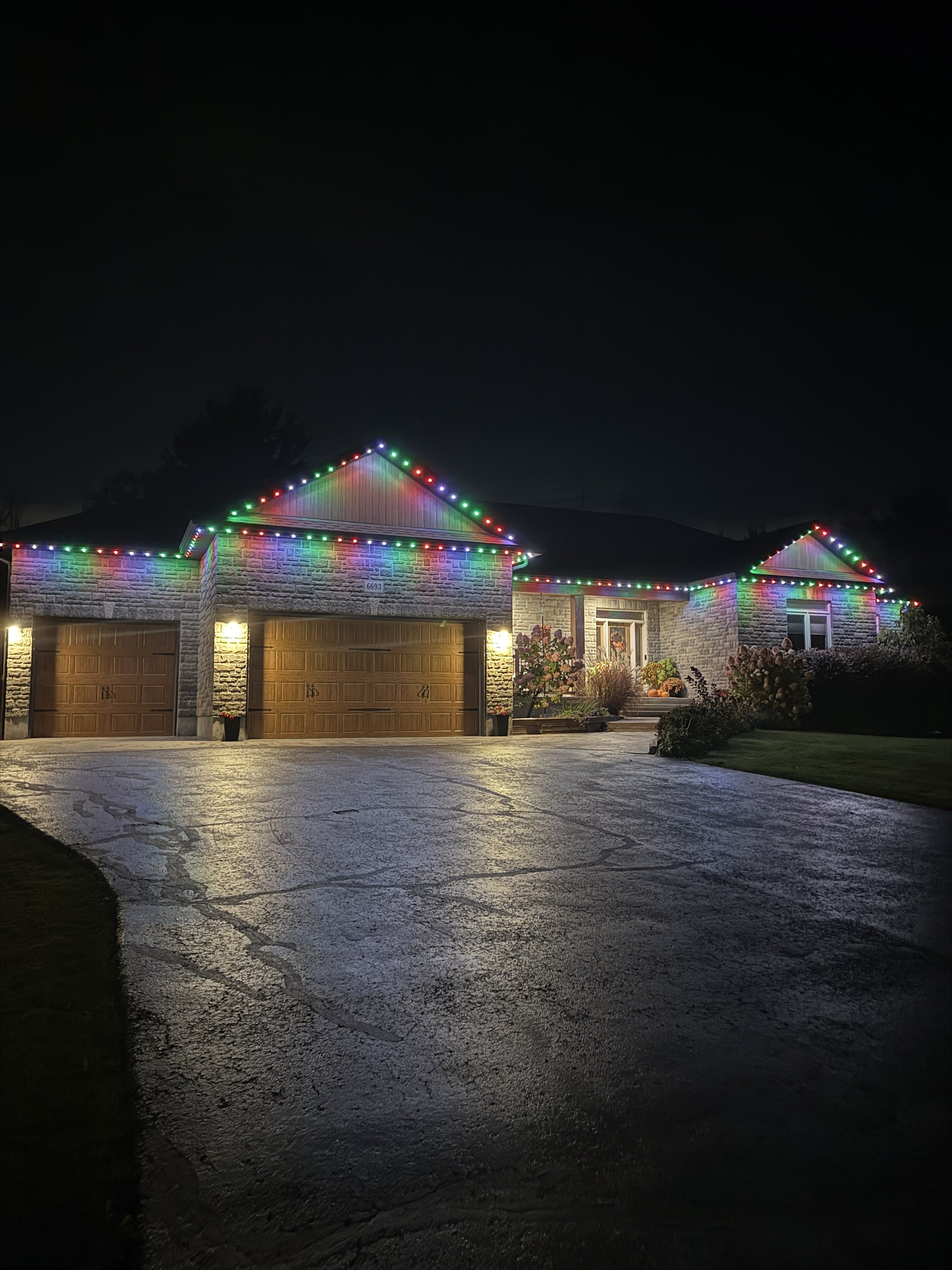 Red, green and white permanent lighting on an Ottawa-area stone bungalow